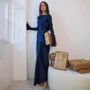 Detail of elegant dark blue satin maxi dress with long sleeves and festive golden gift boxes