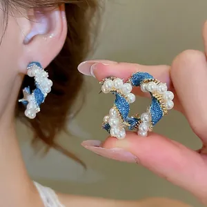 Elegant C-shaped pearl earrings wrapped with blue denim fabric and gold wire
