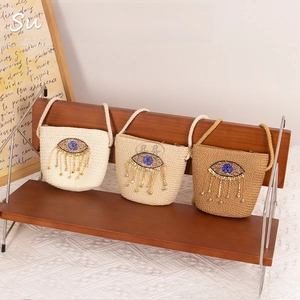 Close-up of woven straw bags with evil eye diamond embroidery and sequin tassels