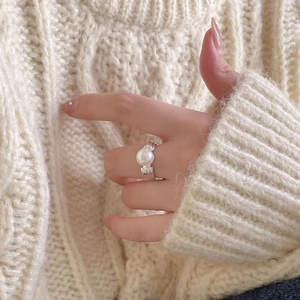 Close-up of a 925 sterling silver pearl ring with a wavy band on a model's hand