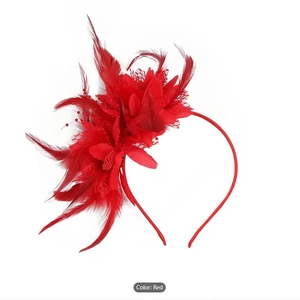 Detailed close-up of a red feather and mesh fascinator headband for wedding parties