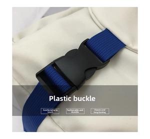 Detail of durable black plastic buckle and navy blue woven strap on white canvas bag