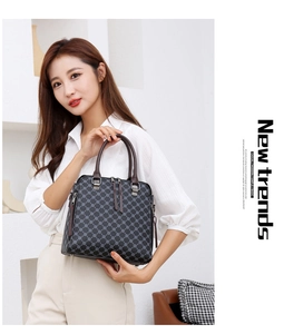 Detail shot of black tote bag with brown handles and patterned texture in modern setting
