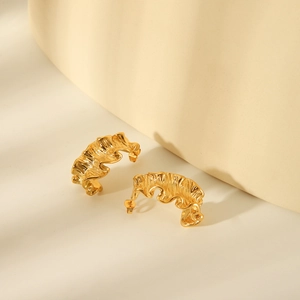 Close-up of golden wavy textured earrings with minimalist geometric crinkle design