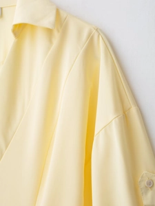 Dettaglio ravvicinato del colletto dell'abito a camicia giallo pallido e polsini bottoni