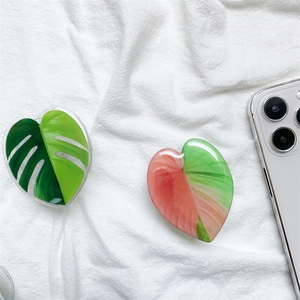 Close-up of heart-shaped monstera leaf phone socket on a white fabric background