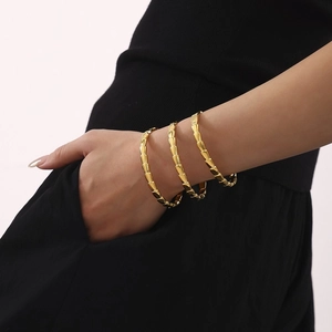 Three 18K gold plated stainless steel snake bone link bracelets worn by a model