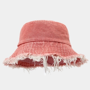 Macro view of frayed edges on distressed coral pink denim fisherman bucket hat