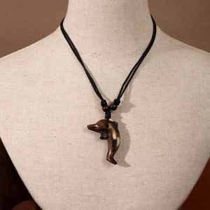 Detail of Maori style dolphin pendant with adjustable black cord and wooden beads on model