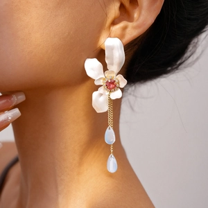 Close-up of elegant flower earrings with red crystal centers and blue teardrop tassels