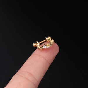 Macro shot of gold butterfly cartilage stud with white zircon held on a fingertip