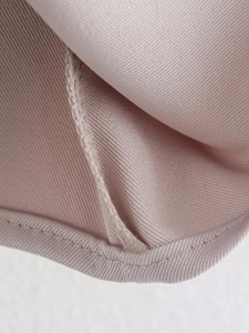 Detail of light pink twill fabric showing professional double-needle stitching on hem