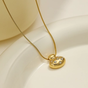 Detail of a gold snake chain necklace with an oval pendant set with sparkling rhinestones