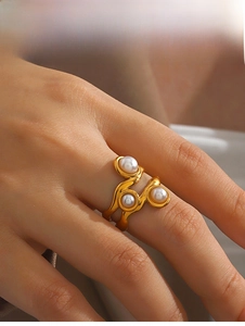 Detail of a gold irregular ring featuring three round pearls on a female finger
