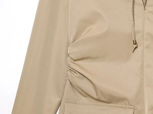 Detalle del vestido corto caqui con tejido fruncido y puntas de cordón doradas