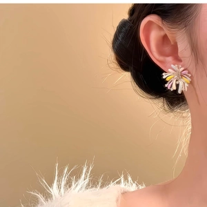 Close-up of colorful firework flower stud earrings with enamel petals and sparkling centers