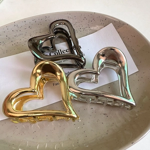 Detailed view of hollow heart hair claws in gold, silver, and black polished finish