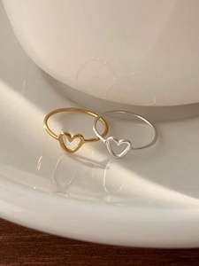 Minimalist gold and silver hollow heart rings displayed on white ceramic plate
