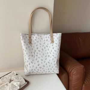 Détail du sac fourre-tout en toile florale avec motifs roses et lanières en cuir