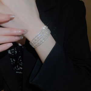 Detailed close-up of layered silver bracelet set with pearls and sparkling zircon accents