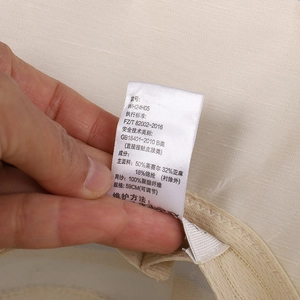 Detail of care label on beige lyocell and linen blend bucket hat showing fabric composition