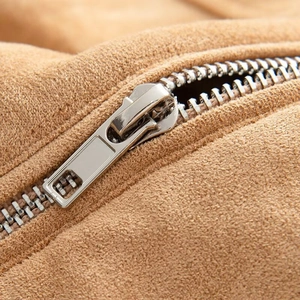 Macro view of a high-quality silver metal zipper on brown faux suede bomber jacket fabric