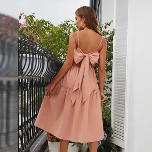 Dusty pink backless maxi dress with a large decorative bow and tiered skirt detail