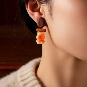 Detailed view of handmade vintage wooden bear pendant earrings worn by a model