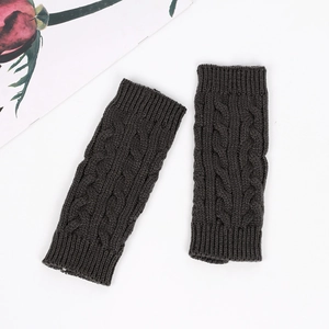 Detail view of dark grey cable knit wrist warmers on a white background with a rose decor