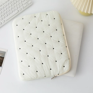 Detail of white quilted laptop sleeve with black polka dots and side zipper closure