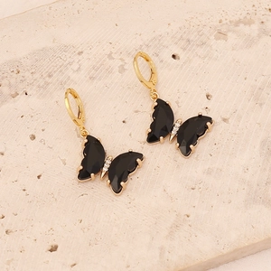 Elegant 18K gold butterfly earrings with black wings and micro-diamonds on stone background