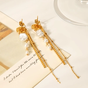 Detail of gold drop earrings featuring Baroque pearls and geometric tassels on vintage card