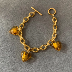 Detail of amber glass heart charms on a gold-plated chain bracelet with an OT toggle clasp