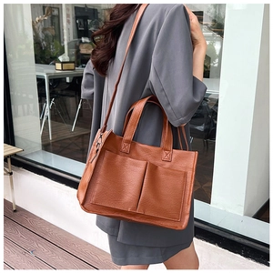 Outdoor street shot of a brown lychee-textured tote bag with dual front pockets