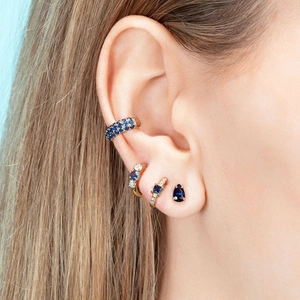 Close-up of gold ear cuff and stud set with deep blue zircons and crystals