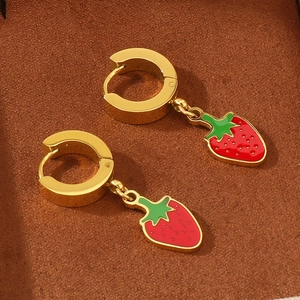 Detail of 18K gold-plated strawberry earrings with red enamel on brown velvet background