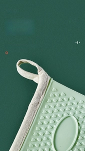 Detail of light green silicone oven mitt showing heart-shaped anti-slip texture and hanging loop