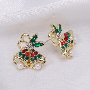 Macro shot of gold festive bell earrings with red and green rhinestones on white satin