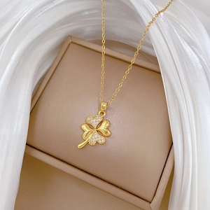 Macro shot of gold four-leaf clover pendant with sparkling diamonds on silk