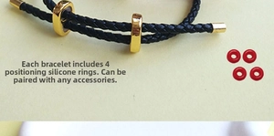 Detail of black braided leather bracelet with gold beads and four red silicone rings