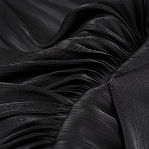 Detailed macro view of black pleated fabric texture with elegant silky luster