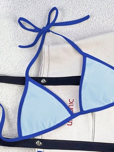 Flat lay of light blue bikini top with navy contrast trim and stylish halter neck tie