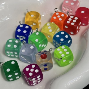 Close-up of colorful resin dice pendants with silver metal hooks in various bright tones