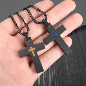 Handheld view of black stainless steel cross necklaces with gold and blue accents