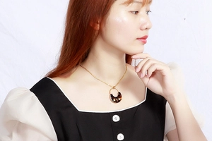 Detail of a vintage tortoise shell semi-circle pendant on a gold chain necklace