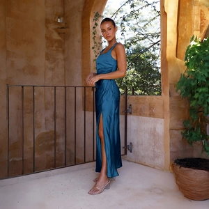 Detail eines eleganten Satin-Maxikleids in Pfauenblau mit hohem Seitenschlitz