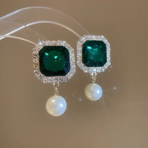 Macro detail of vintage emerald square gemstone earring with white pearl and gold plating