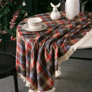 Festive red and blue plaid round tablecloth with tassel fringe in a cozy Christmas setting