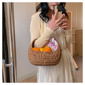 Brown rattan basket bag decorated with pink silk scarf and fresh lemons inside