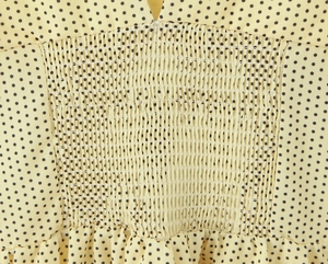 Détail du tissu jaune à pois noirs montrant la texture élastique froncée